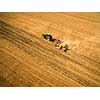 Aerial view of a tractor working a field after harvest