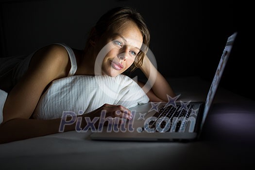 Pretty, young woman using her laptop computer in bed (color toned image; shallow DOF) Pretty, young woman using her laptop computer in bed (color toned image; shallow DOF)