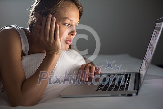 Pretty, young woman using her laptop computer in bed (color toned image; shallow DOF) Pretty, young woman using her laptop computer in bed (color toned image; shallow DOF)
