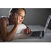 Pretty, young woman using her laptop computer in bed (color toned image; shallow DOF)
