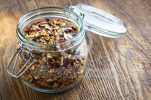 Homemade granola in open glass jar on rustic wooden background Homemade granola in open glass jar on rustic wooden background