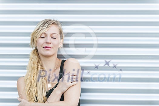 Portrait of young blonde woman with eyes closed against metal background and copy space Portrait of young blonde woman with eyes closed against metal background and copy space