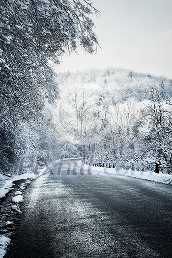 Icy winter road leading downhill through forest Icy winter road leading downhill through forest