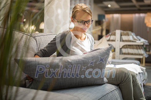 Pretty, young woman choosing the right furniture for her apartment in a modern home furnishings store (color toned image; shallow DOF) Pretty, young woman choosing the right furniture for her apartment in a modern home furnishings store (color toned image; shallow DOF)