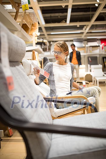 Pretty, young woman choosing the right furniture for her apartment in a modern home furnishings store (color toned image; shallow DOF) Pretty, young woman choosing the right furniture for her apartment in a modern home furnishings store (color toned image; shallow DOF)
