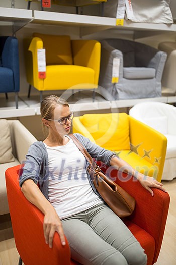 Pretty, young woman choosing the right furniture for her apartment in a modern home furnishings store (color toned image; shallow DOF) Pretty, young woman choosing the right furniture for her apartment in a modern home furnishings store (color toned image; shallow DOF)