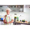 Senior woman cooking in the kitchen - eating and cooking healthy for her family; putting some potates in the oven, enjoying active retirement (shallow DOF; color toned image)