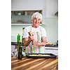 Senior woman cooking in the kitchen - eating and cooking healthy for her family; putting some potates in the oven, enjoying active retirement (shallow DOF; color toned image)