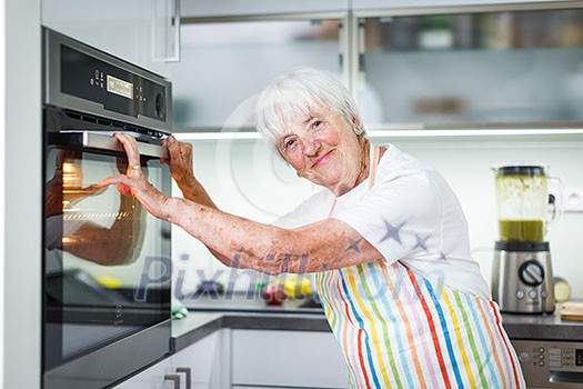 Senior woman cooking in the kitchen - eating and cooking healthy for her family; putting some potates in the oven, enjoying active retirement (shallow DOF; color toned image) Senior woman cooking in the kitchen - eating and cooking healthy for her family; putting some potates in the oven, enjoying active retirement (shallow DOF; color toned image)