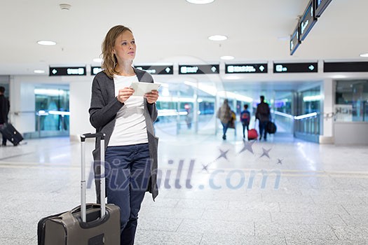 Young female passenger at the airport, using her tablet computer while waiting for her flight (color toned image) Young female passenger at the airport, using her tablet computer while waiting for her flight (color toned image)