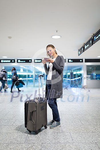 Young female passenger at the airport, using her tablet computer while waiting for her flight (color toned image) Young female passenger at the airport, using her tablet computer while waiting for her flight (color toned image)