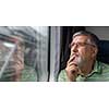 Senior man enjoying a train travel - leaving his car at home, he savours the time spent travelling, looks out of the window, has time to admire the landscape passing by