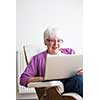 Portrait of a senior woman at home - Laughing at something on her laptop computer, sitting in her favorite chair, enjoying retirement