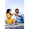 Young romantic couple celebrating with wine at the beach looking at each other