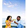 Young romantic couple celebrating with wine at the beach with copyspace