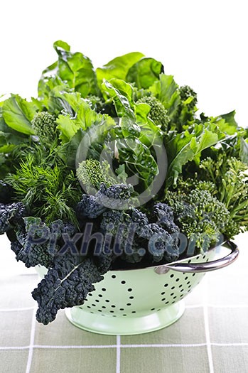 Dark green leafy fresh vegetables in metal colander Dark green leafy fresh vegetables in metal colander