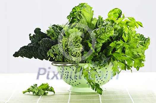 Dark green leafy fresh vegetables in metal colander Dark green leafy fresh vegetables in metal colander