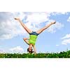 Young teenage girl doing cartwheel in a summer meadow