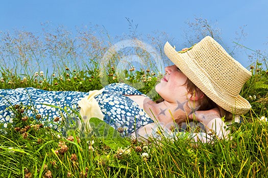 Young teenage girl resting on summer meadow in straw hat Young teenage girl resting on summer meadow in straw hat