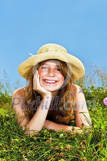 Young teenage girl laying in summer meadow resting chin on hand smelling flower Young teenage girl laying in summer meadow resting chin on hand smelling flower
