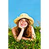 Young teenage girl laying in summer meadow resting chin on hand smelling flower