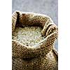 Raw long grain white rice grains in burlap bag