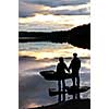 Sun setting over tranquil lake with people watching in silhouette