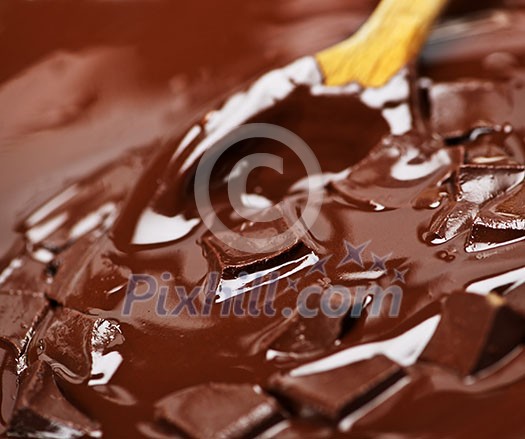 Wooden spoon stirring melting rich chocolate chunks Wooden spoon stirring melting rich chocolate chunks
