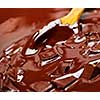Wooden spoon stirring melting rich chocolate chunks