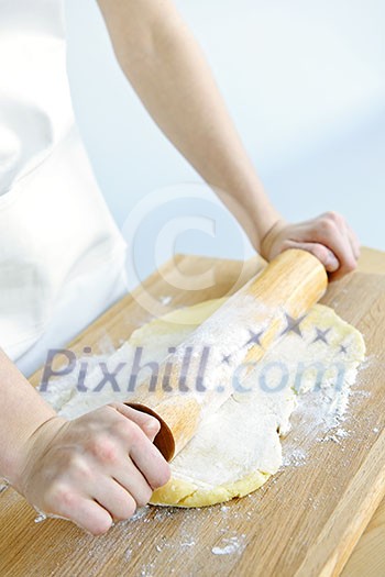 Spreading out cookie dough with wooden rolling pin Spreading out cookie dough with wooden rolling pin