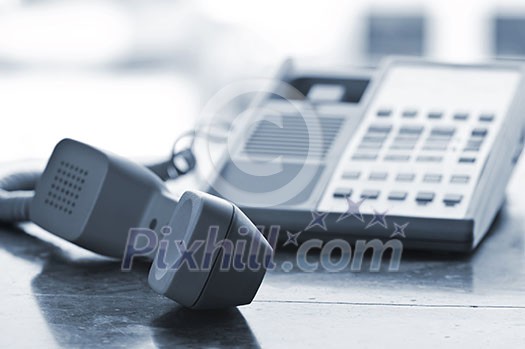 Telephone handset off the hook on desk Telephone handset off the hook on desk