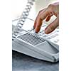Close up of fingers dialing a desktop telephone