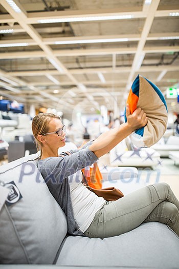 Pretty, young woman choosing the right furniture for her apartment in a modern home furnishings store (color toned image; shallow DOF) Pretty, young woman choosing the right furniture for her apartment in a modern home furnishings store (color toned image; shallow DOF)