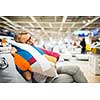 Pretty, young woman choosing the right furniture for her apartment in a modern home furnishings store (color toned image; shallow DOF)