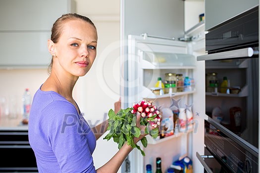 Pretty, young woman taking fresh vegetables from her fridge - being on a gluten free vegan diet does not seem to be a problem for her (shallow DOF; color toned image) Pretty, young woman taking fresh vegetables from her fridge - being on a gluten free vegan diet does not seem to be a problem for her (shallow DOF; color toned image)