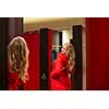 Young woman shopping in a fashion store, trying on some clothes she likes (color toned image; shallow DOF)