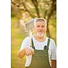 Portrait of a handsome senior man gardening in his garden, on a lovely spring day (color toned image)