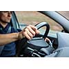 Male driver's hands driving a car on a highway (color toned image; shallow DOF)