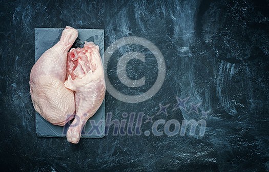 Raw chicken thigh on black stone plate Raw chicken thigh on black stone plate
