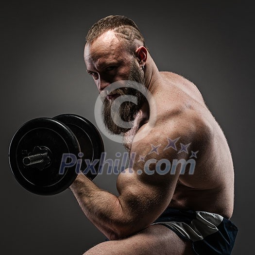 Muscular bearded bodybuilder guy doing exercises with dumbbells Muscular bearded bodybuilder guy doing exercises with dumbbells