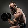 Muscular bearded bodybuilder guy doing exercises with dumbbells