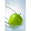 green apple in glass plate on blue background