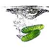 green cucumbers dropped into water isolated on white