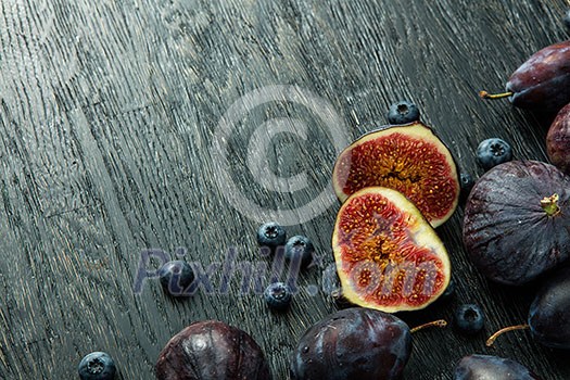 sliced figs and ripe berries on a dark wooden background sliced figs and ripe berries on a dark wooden background