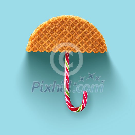 Umbrella made of waffle and Christmas candy on a blue background. Umbrella made of waffle and Christmas candy on a blue background.