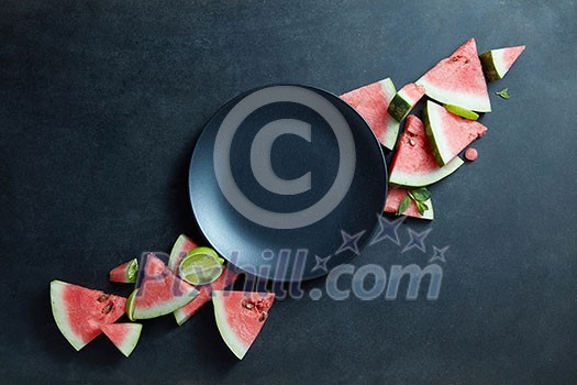 black plate and slices of fresh watermelon on a black background black plate and slices of fresh watermelon on a black background