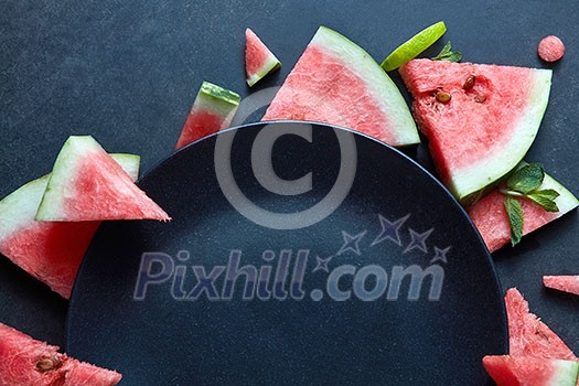 slices of watermelon placed near the plate black isolated on black slices of watermelon placed near the plate black isolated on black
