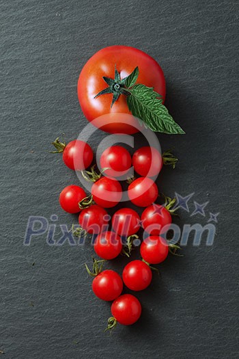 bunch of cherry tomatoes with leaves isolated on a black concrete background bunch of cherry tomatoes with leaves isolated on a black concrete background