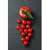 bunch of cherry tomatoes with leaves isolated on a black concrete background