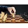 Hand moving a knight chess piece on wooden chessboard